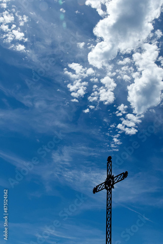 Iron cross depicting the sacred heart of Jesus on a sunny blue sky background. Croix de fer représentant le cœur sacré de Jésus sur fond de ciel bleu ensoleillé.