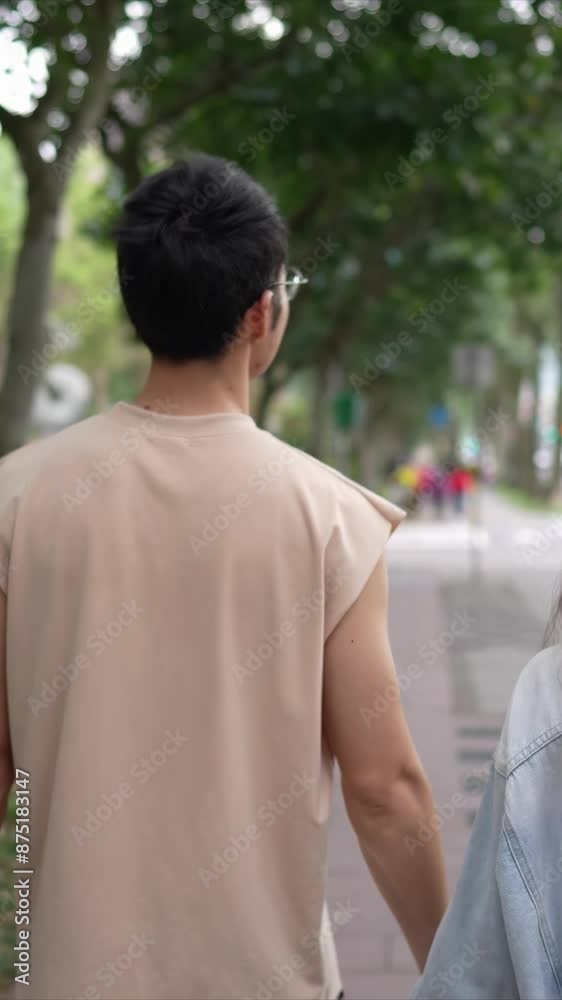A vertical slow-motion video of a young Taiwanese couple in their twenties walking through the streets of Xinyi District, Taipei City on a spring afternoon. The man is wearing a sleeveless top A vertical slow-motion video of a young Taiwanese couple in their twenties walking through the streets of Xinyi District, Taipei City on a spring afternoon. The man is wearing a sleeveless top