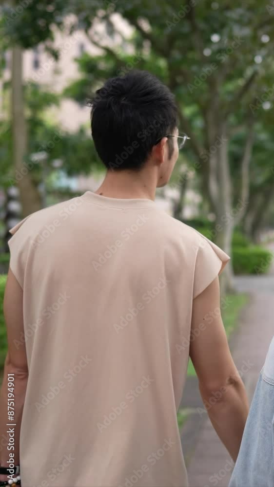 A vertical slow-motion video of a young Taiwanese couple in their twenties walking through the streets of Xinyi District, Taipei City on a spring afternoon. The man is wearing a sleeveless top A vertical slow-motion video of a young Taiwanese couple in their twenties walking through the streets of Xinyi District, Taipei City on a spring afternoon. The man is wearing a sleeveless top