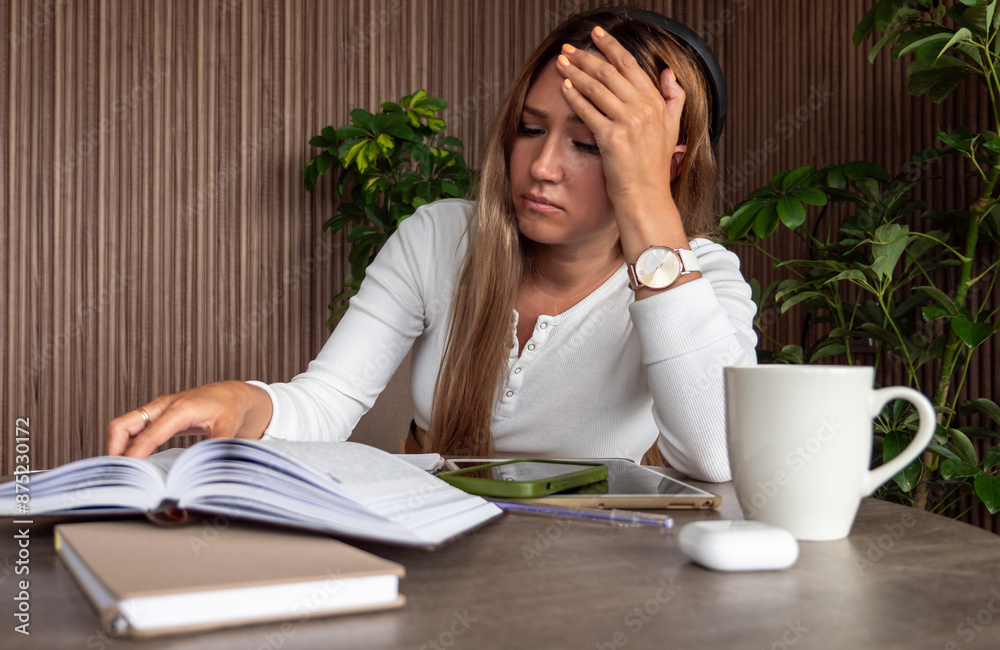 Woman feeling stressed while studying with books, notebook, and cup of coffee at desk. Woman feeling stressed while studying with books, notebook, and cup of coffee at desk.