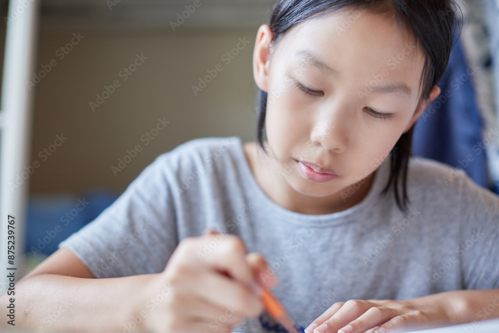 夏の家のリビングで夢中で勉強する小学生の女の子の様子