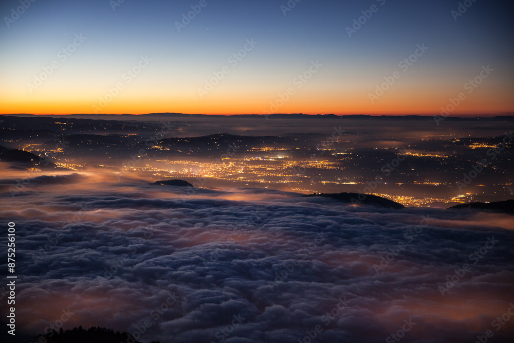View in the evening from Mount Rigi to Lake Zug, which is covered with a thick layer of fog and the lights of the villages below shine through the fog. View in the evening from Mount Rigi to Lake Zug, which is covered with a thick layer of fog and the lights of the villages below shine through the fog.