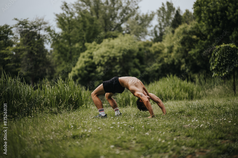 Athletic man showing flexibility by performing a back bend in a green, lush outdoor park, emphasizing fitness and nature. Athletic man showing flexibility by performing a back bend in a green, lush outdoor park, emphasizing fitness and nature.
