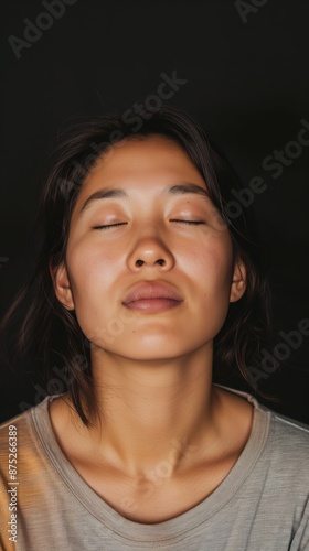 An Asian woman with closed eyes, possibly meditating, during Mental Illness Awareness Week