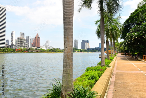 Bangkok, Thailand. July 6, 2024 : Cityscape view of Lake Ratchada situated in the Benjakitti Park with flowers, Benchakitti Forest Park is new landmark. On a hot, sunny morning during the wet season. photo