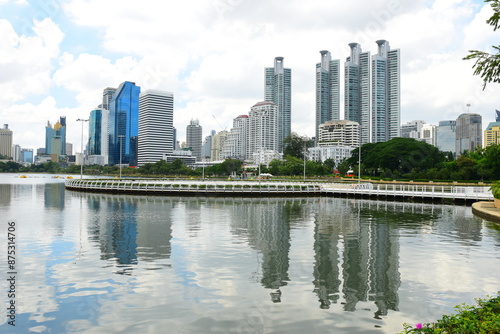 Bangkok, Thailand. July 6, 2024 : Cityscape view of Lake Ratchada situated in the Benjakitti Park with flowers, Benchakitti Forest Park is new landmark. On a hot, sunny morning during the wet season. photo