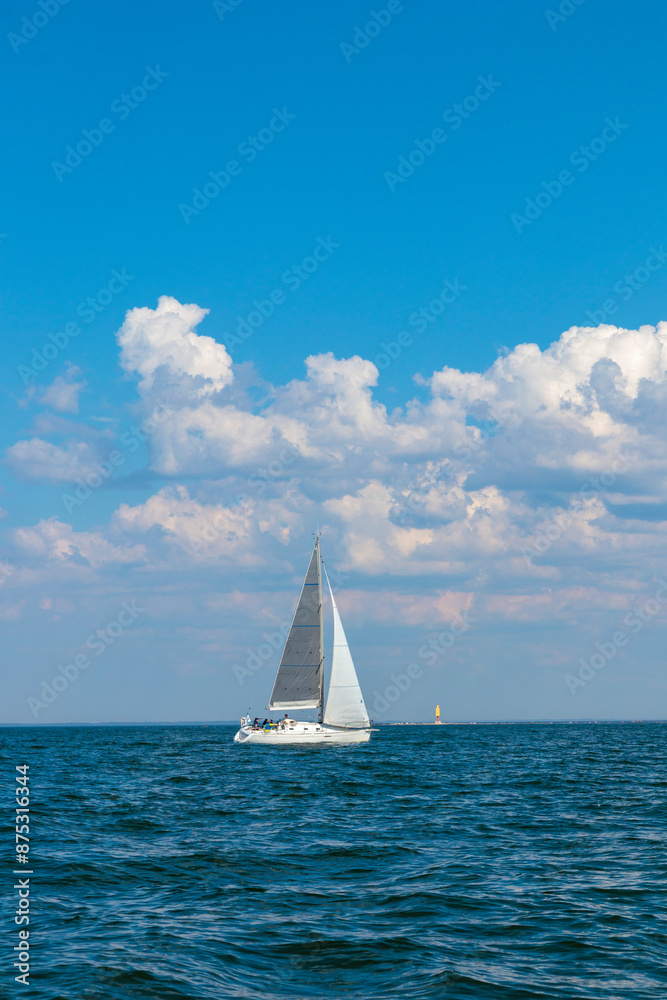 Obraz premium uWhite sloop rigged yacht sailing in the Baltic sea at sunset. Blye sky after the storm, soft sunlight. Transportation, travel, cruise, sport, recreation, leisure activity, racing, regatta