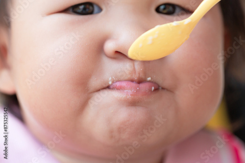 Wallpaper Mural mother feeding child,Baby girl eating blend mashed food sitting, on high chair, mother feeding child, hand with spoon for vegetable lunch, baby weaning, first solid food for Torontodigital.ca