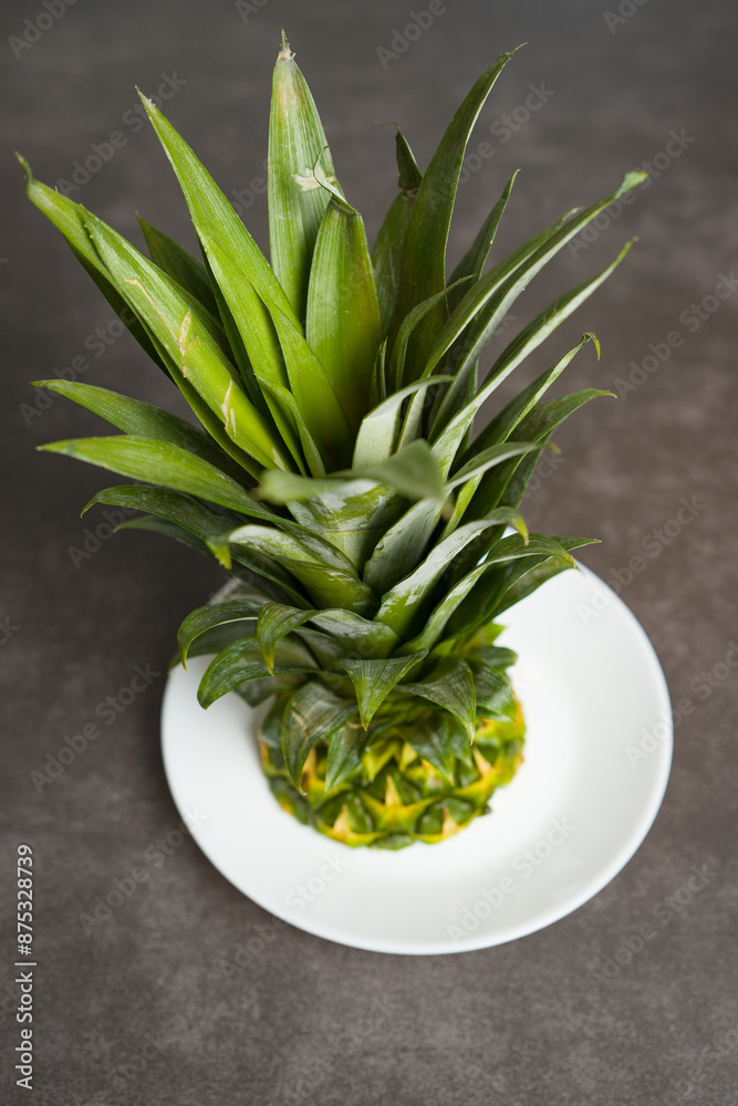 Fototapeta premium Pineapple leaves and fruit remains on a plate. Pineapple close-up on the table.