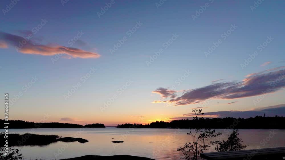 A wide shot of a beautiful archipelago in Pori, Finland on a sunny day. The camera is positioned on a rocky outcropping with trees in the foreground, and the view looks out over a large body of water A wide shot of a beautiful archipelago in Pori, Finland on a sunny day. The camera is positioned on a rocky outcropping with trees in the foreground, and the view looks out over a large body of water