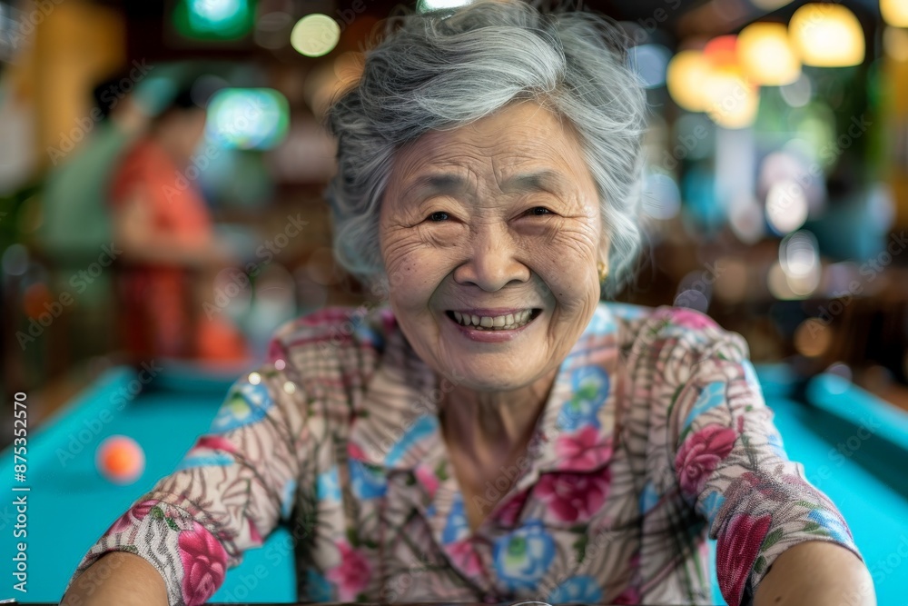 An elderly woman with a beaming smile plays a game of billiards indoors, showcasing her happiness and joy with life, while dressed in a floral shirt. An elderly woman with a beaming smile plays a game of billiards indoors, showcasing her happiness and joy with life, while dressed in a floral shirt.