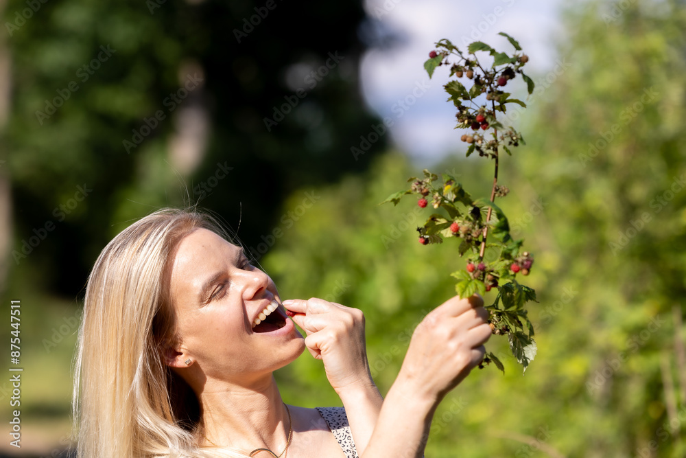 Young beautiful woman eating wild raspberries in the forest Young beautiful woman eating wild raspberries in the forest
