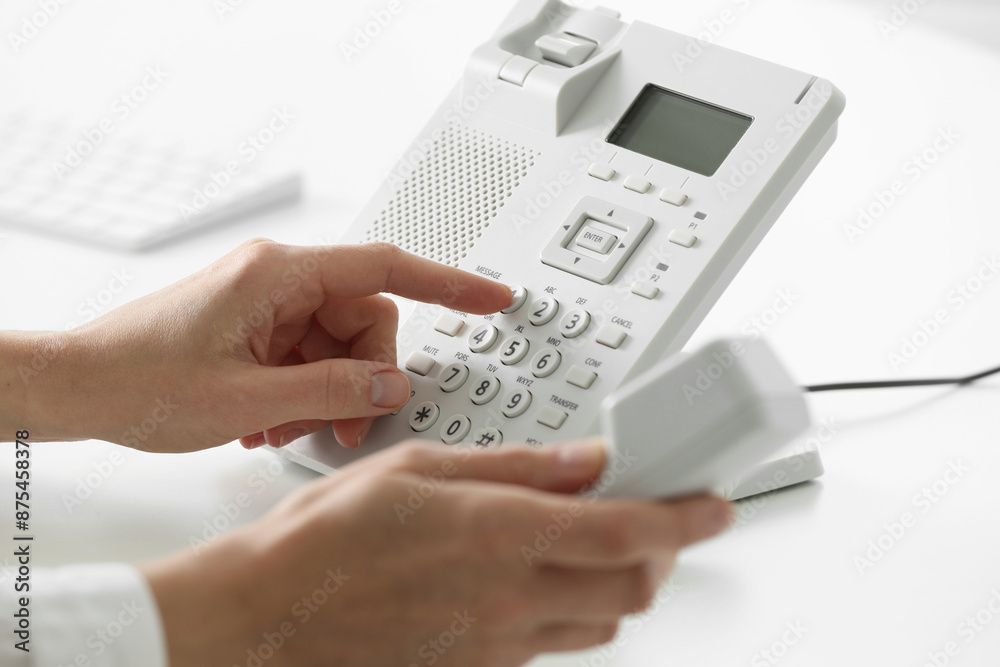 Assistant dialing number on telephone against blurred background, closeup Assistant dialing number on telephone against blurred background, closeup