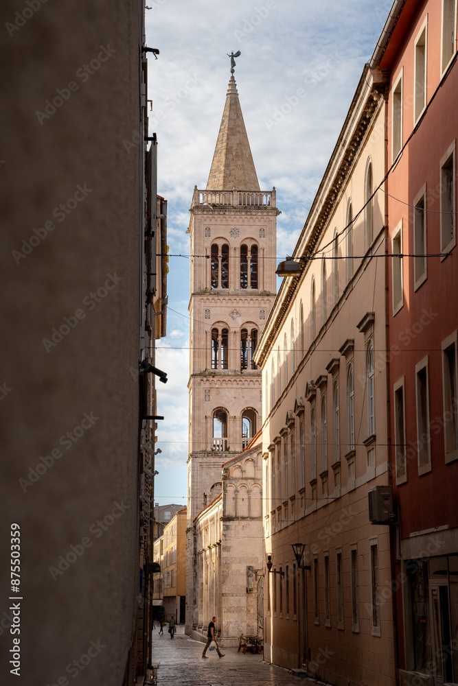 Der Kirchturm der Kirche St. Donatus (Crkva sv. Donatus) in mitten der historischen Altstadt von Zadar in Kroatien, im Vordergrund die engen Gassen der Innenstadt mit einzelnen Touristen (Hochformat) Der Kirchturm der Kirche St. Donatus (Crkva sv. Donatus) in mitten der historischen Altstadt von Zadar in Kroatien, im Vordergrund die engen Gassen der Innenstadt mit einzelnen Touristen (Hochformat)
