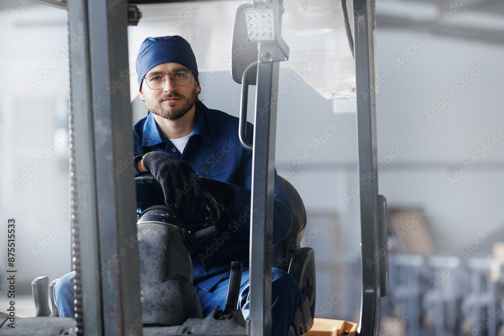 Happy young man in uniform driver of forklift on warehouse production Happy young man in uniform driver of forklift on warehouse production