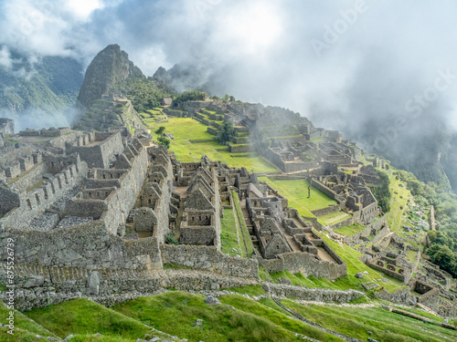 Overview of the city of Machu Picchu in the early morning mist with the Andes Mountains in the background.