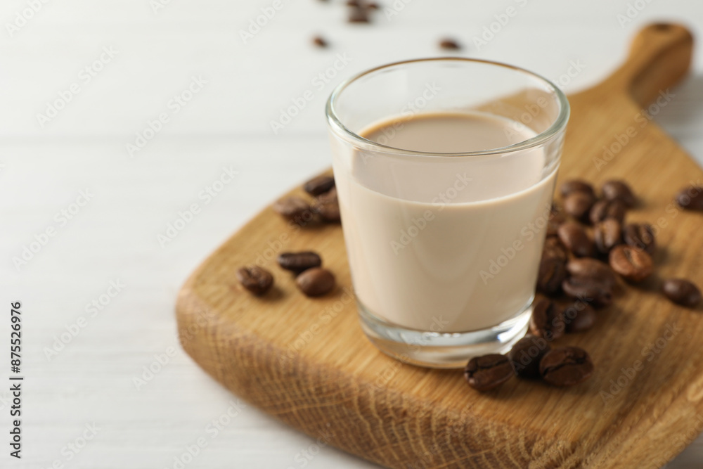Coffee cream liqueur in glass and beans on white wooden table, closeup. Space for text Coffee cream liqueur in glass and beans on white wooden table, closeup. Space for text