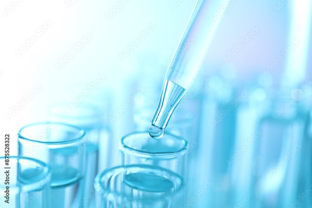 Dripping liquid from pipette into test tube on light blue background, closeup Dripping liquid from pipette into test tube on light blue background, closeup