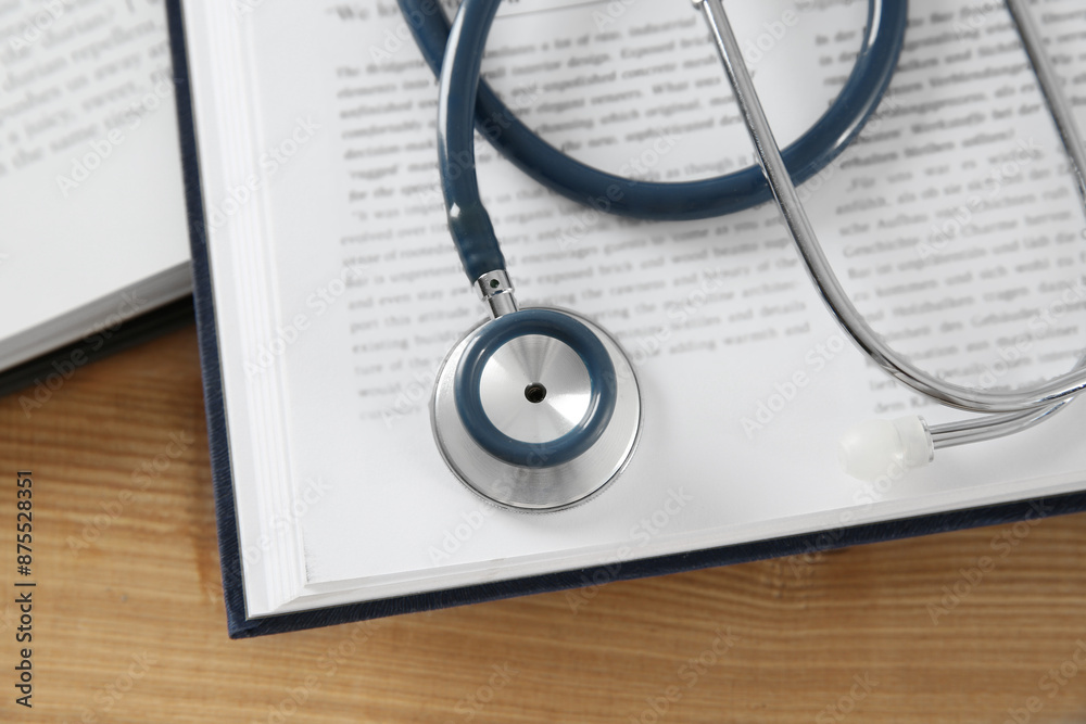One new medical stethoscope and books on wooden table, top view One new medical stethoscope and books on wooden table, top view