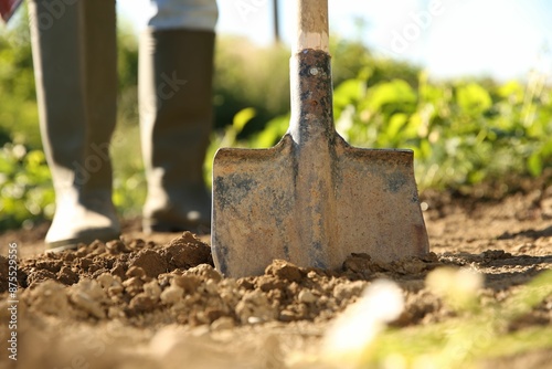 Farmer digging soil with shovel on sunny day, closeup