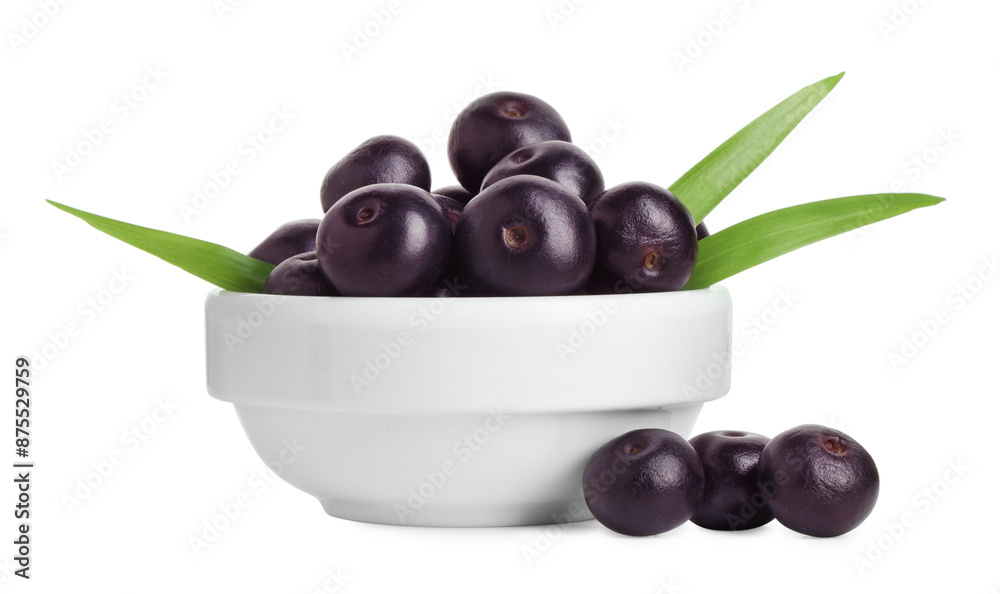 Fresh ripe acai berries in bowl and green leaves isolated on white