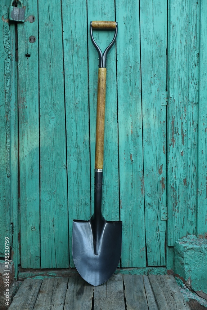 Metal shovel near turquoise wooden wall. Gardening tool Metal shovel near turquoise wooden wall. Gardening tool