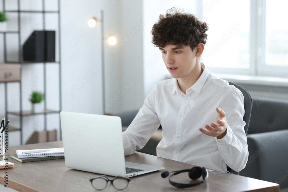 Teenager having video chat via laptop at table indoors. Remote work Teenager having video chat via laptop at table indoors. Remote work