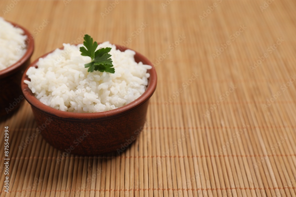 Bowls of delicious boiled rice with parsley on bamboo mat. Space for text Bowls of delicious boiled rice with parsley on bamboo mat. Space for text