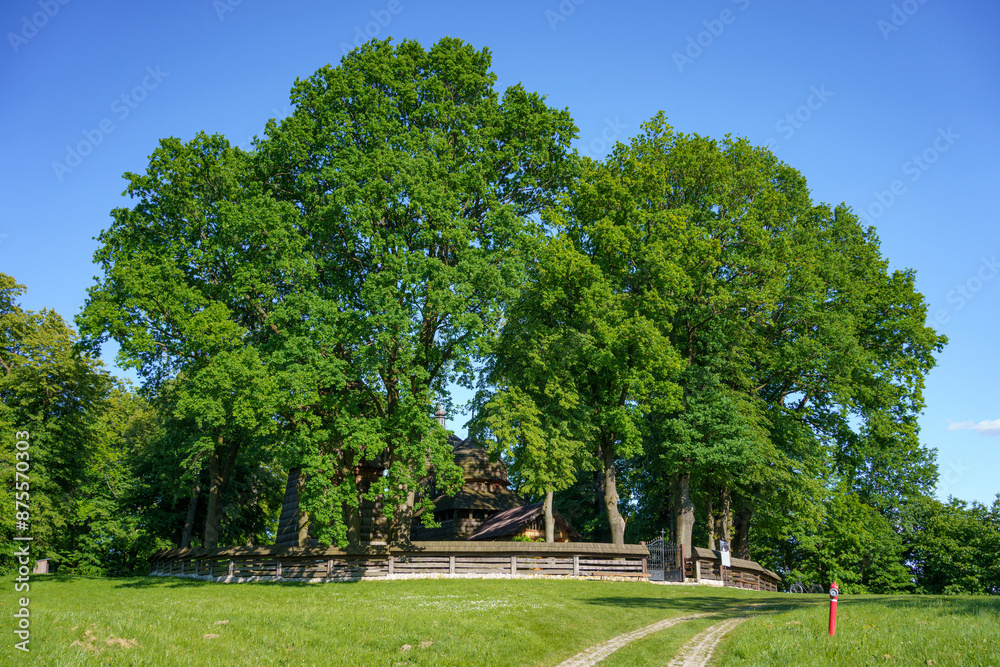 Chotyniec, Subcarpathian, Poland - 12 May 2024: wooden Greek Catholic Church of the Nativity of the Holy Mother of God listed as a Unesco World Heritage Site surrounded by old linden trees Chotyniec, Subcarpathian, Poland - 12 May 2024: wooden Greek Catholic Church of the Nativity of the Holy Mother of God listed as a Unesco World Heritage Site surrounded by old linden trees