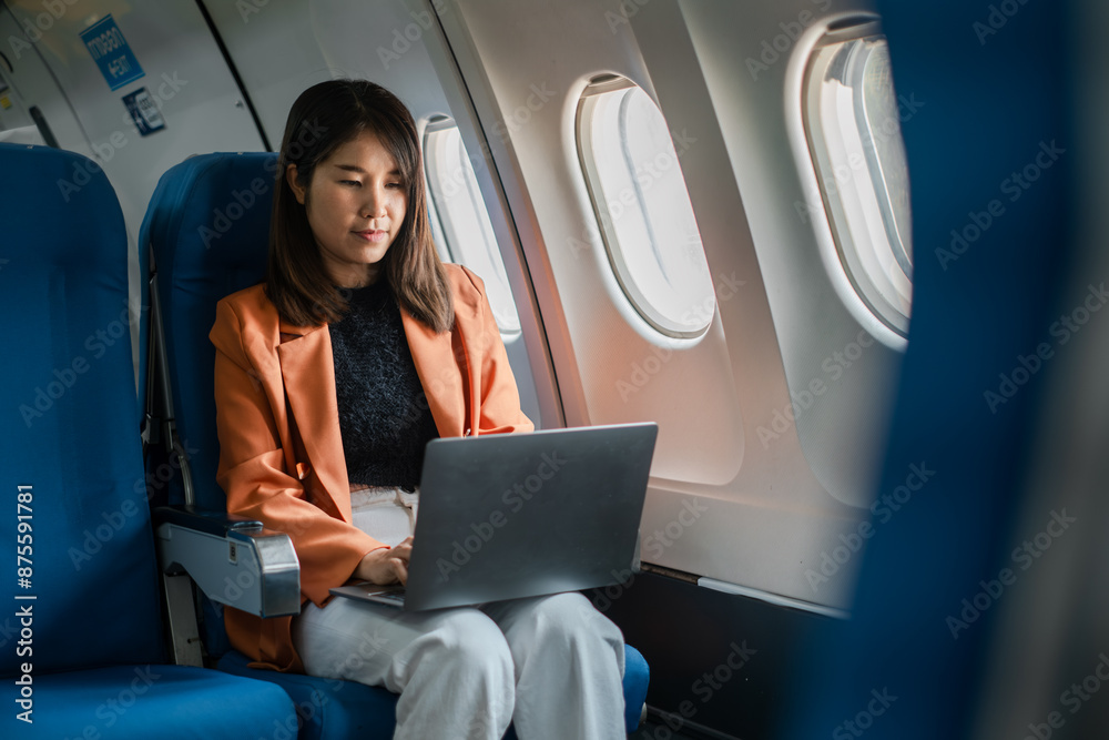 Professional woman using a laptop while traveling on an airplane, showcasing modern business travel and technology. Professional woman using a laptop while traveling on an airplane, showcasing modern business travel and technology.