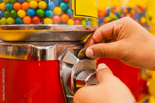Obraz na plátně Person inserting a coin into a colorful gumball machine