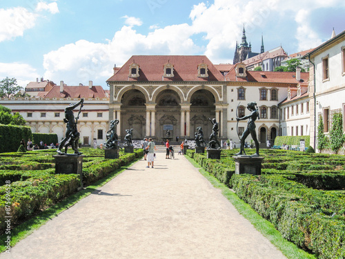 Tourists walk along the decorative alley decorated with many statues in a decorative park at Wallenstein Palace building in Prague in Czech Republic photo