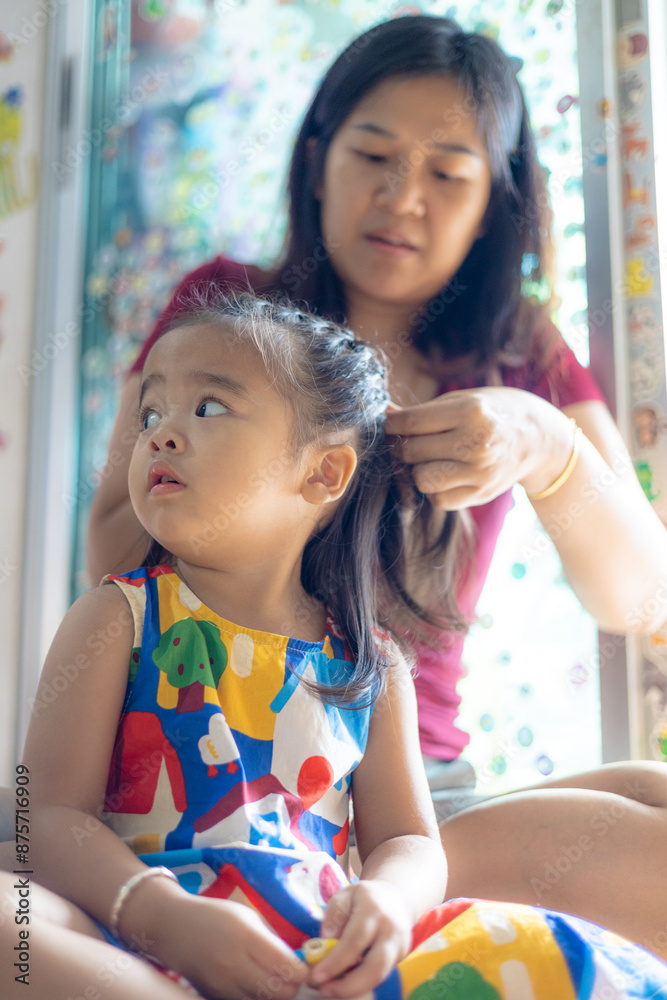 Obraz premium Beautiful asian mom with adorable daughter hair dressing in cozy room