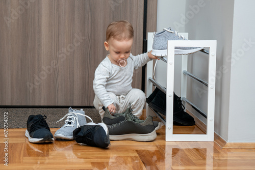 A child puts away adults' shoes at the entrance to the apartment. The concept of accustoming to work photo