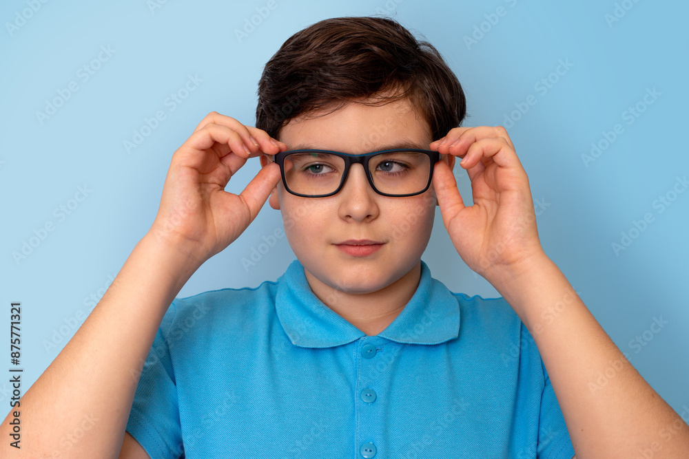 Close up of dark haired boy in glasses on light-blue background, looking away Close up of dark haired boy in glasses on light-blue background, looking away
