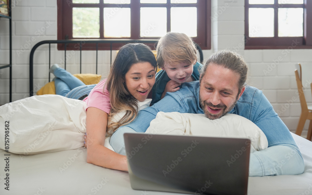 Happy family people leisure in bedroom together. Father and mother with son relaxing and using laptop on bed Happy family people leisure in bedroom together. Father and mother with son relaxing and using laptop on bed