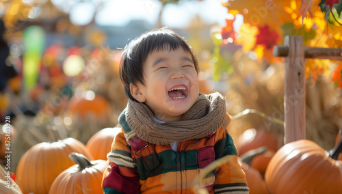 Happy kid smiling in pumpkins at fall festival