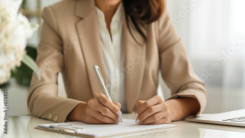 writing in a planner at a clean, minimalist table, soft white and beige tones,