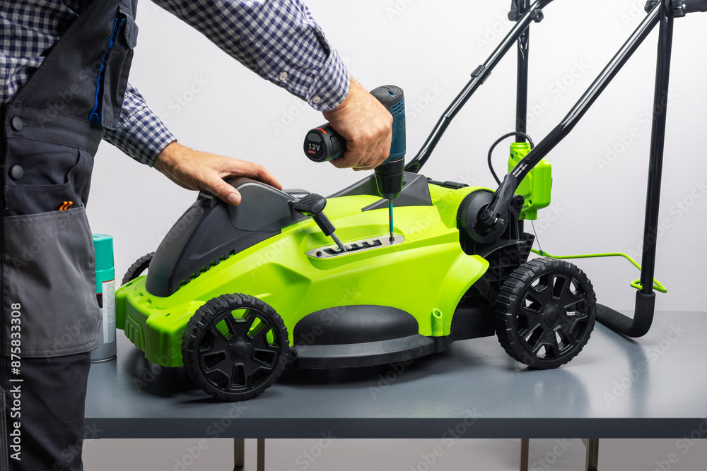 Lawnmower repair. The man is repairing the mower in the work shop. Lawnmower repair. The man is repairing the mower in the work shop.