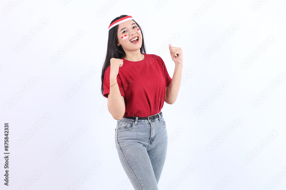Young Asian woman clenched both fist to celebrate Indonesia independence day on August 17, looking at camera with confident and excited expression wearing red top and flag headband Young Asian woman clenched both fist to celebrate Indonesia independence day on August 17, looking at camera with confident and excited expression wearing red top and flag headband