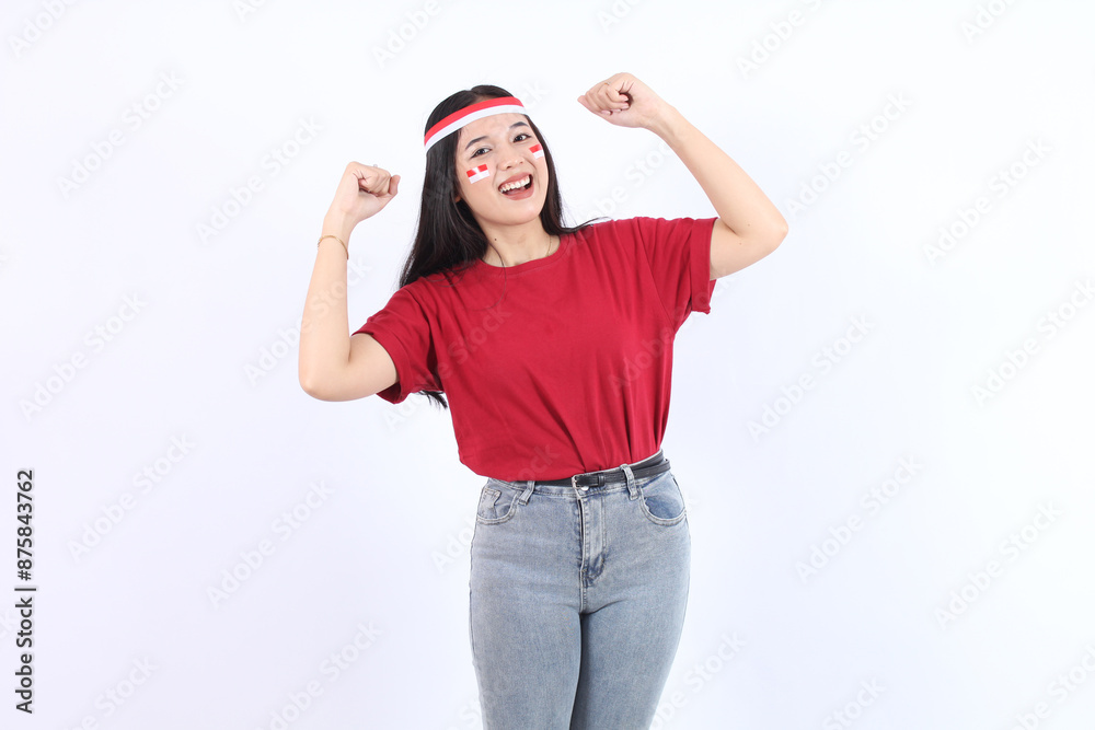 Young Asian woman clenched both fist to celebrate Indonesia independence day on August 17, looking at camera with confident and excited expression wearing red top and flag headband Young Asian woman clenched both fist to celebrate Indonesia independence day on August 17, looking at camera with confident and excited expression wearing red top and flag headband