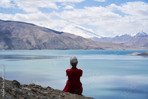 rear view of an Uyghur lady sitting and overlooking Baisha Lake in Xinjiang, China