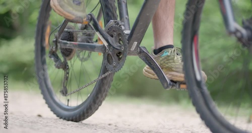 Abstract mountainbiker riding by. Man riding a mountainbike on a dusty dirth road path. Closeup pedal shoe and gear shift. Recorded at 120 fps on cinema camera. photo