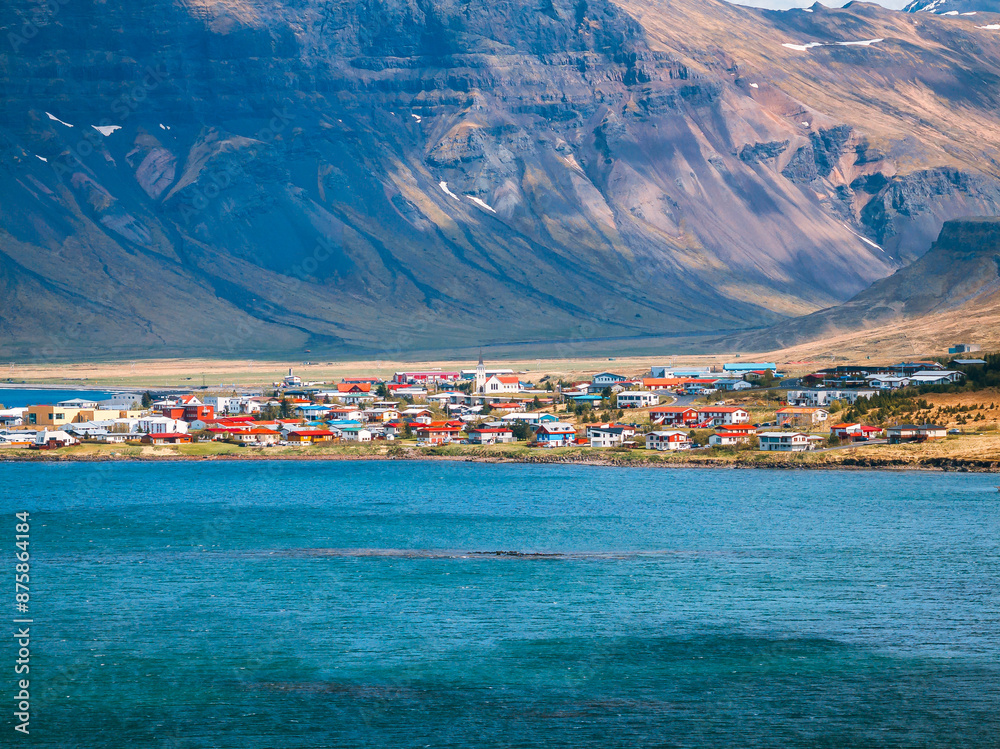 Fototapeta premium Charming coastal town with colorful houses nestled against majestic mountains in Iceland