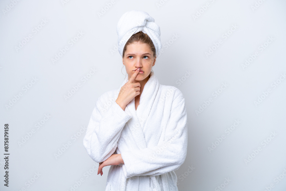 Teenager Russian girl in a bathrobe isolated on white background having doubts while looking up Teenager Russian girl in a bathrobe isolated on white background having doubts while looking up