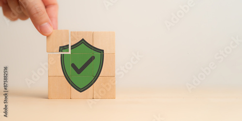 Work safety concept, hazards, protections, health and regulation. Data security and privacy. Hand placing wooden cubes with green protect shield symbol on white background. Workplace safety. photo