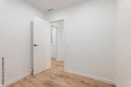 Empty modern room with open door and wooden floor offers clean stylish space for buyers or renters