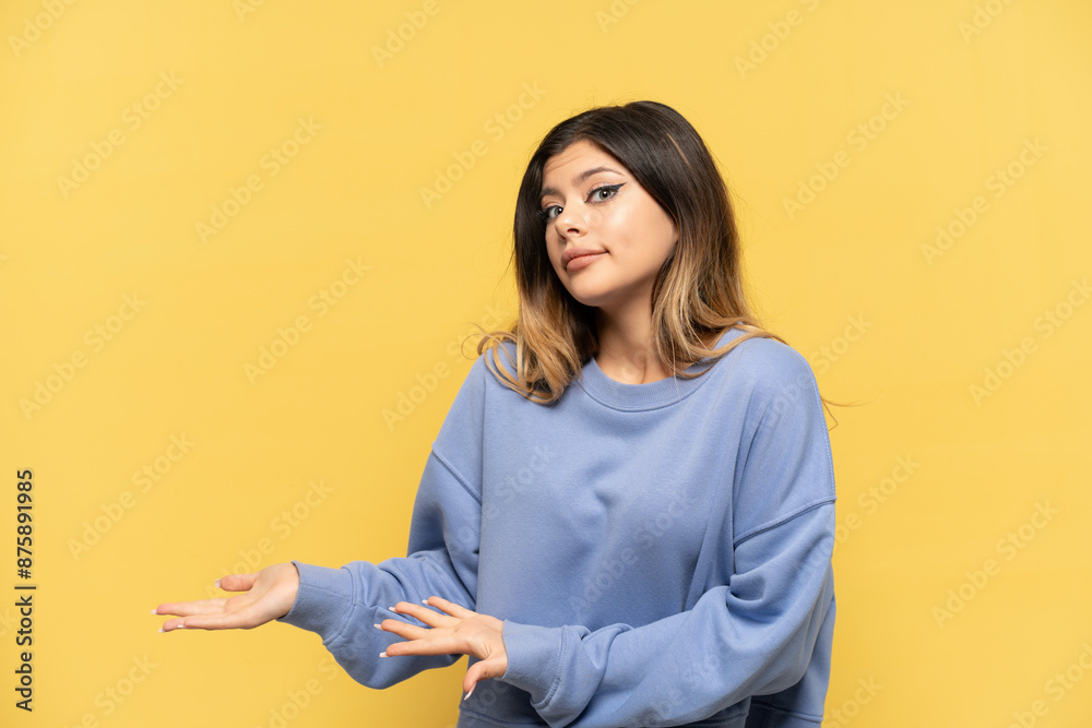 Young Russian girl isolated on yellow background with surprise expression while looking side Young Russian girl isolated on yellow background with surprise expression while looking side