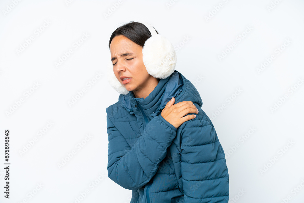 Young hispanic woman wearing a winter earmuffs isolated on white background suffering from pain in shoulder for having made an effort Young hispanic woman wearing a winter earmuffs isolated on white background suffering from pain in shoulder for having made an effort