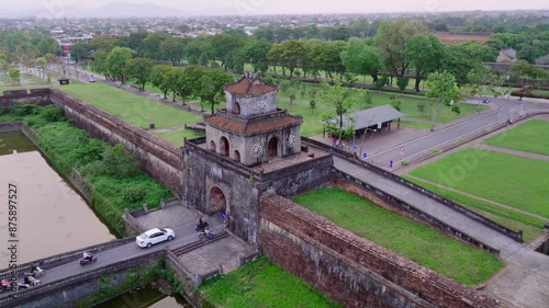 This footage captures the entrance to Hue Imperial City in Vietnam, where modern vehicles drive towards the historic gate. The shot showcases the blend of history and contemporary life.